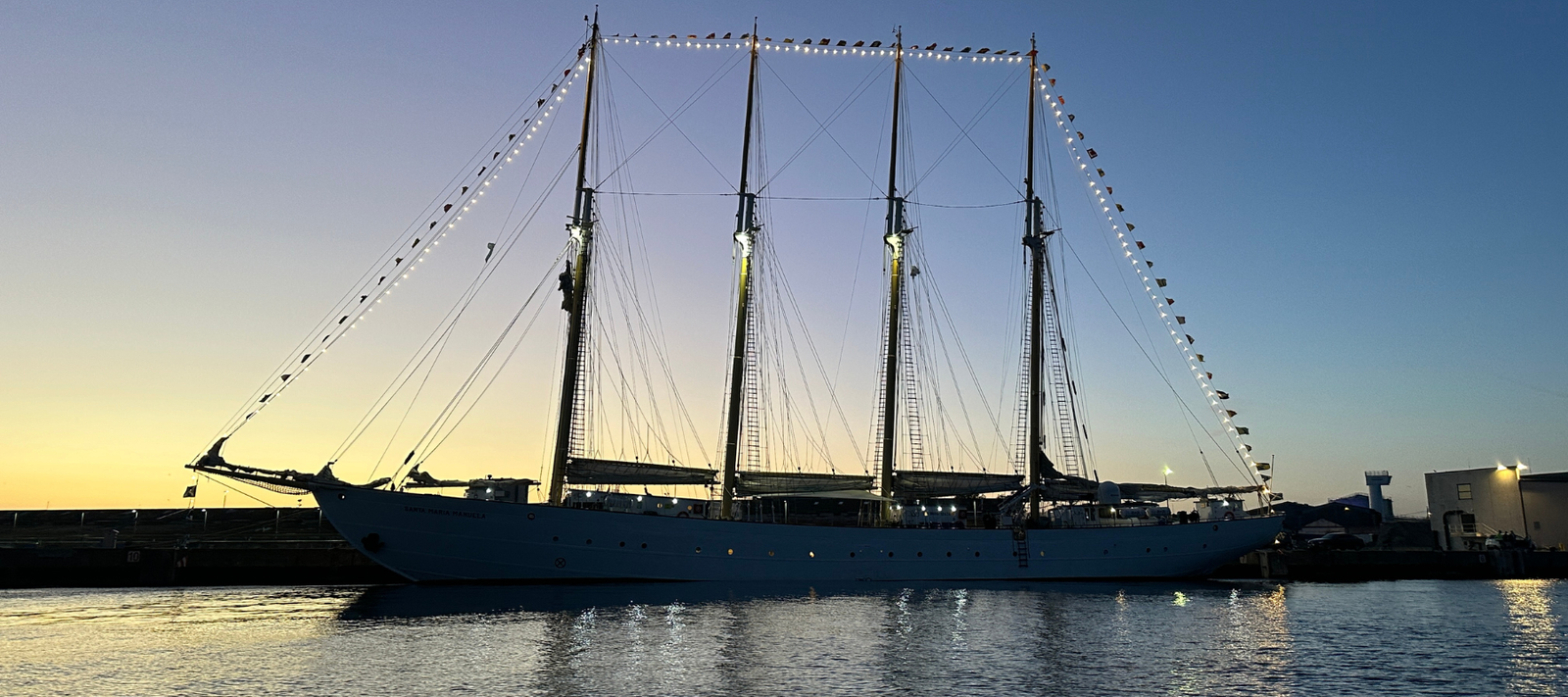 Sailing ship docked at sunset with a clear sky