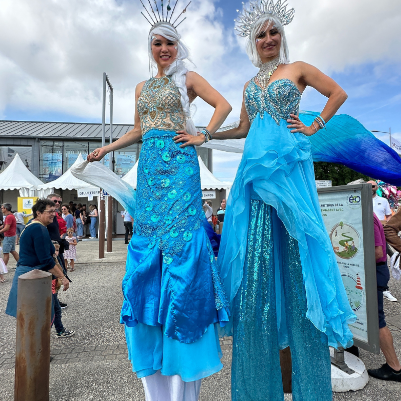 Two women in blue costumes with sparkles on a street.